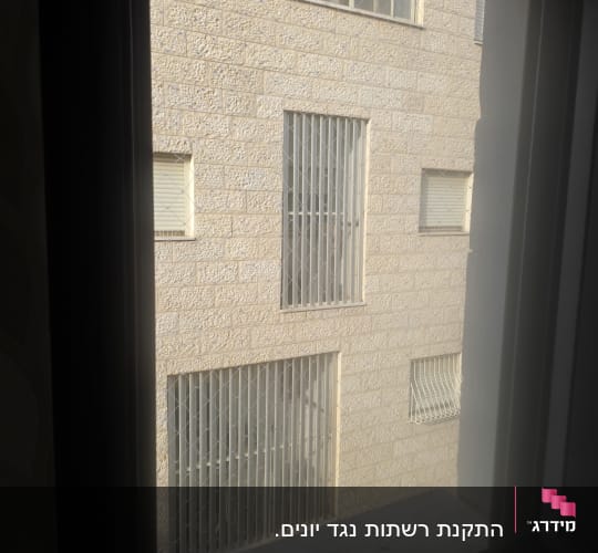 רשת יונים מותקנת על חלון למניעת כניסת יונים